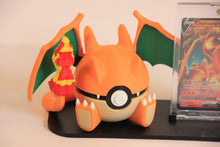 The Charizard Pokéball up close: orange with a cream belly, green wings, clawed feet and the tail flame.