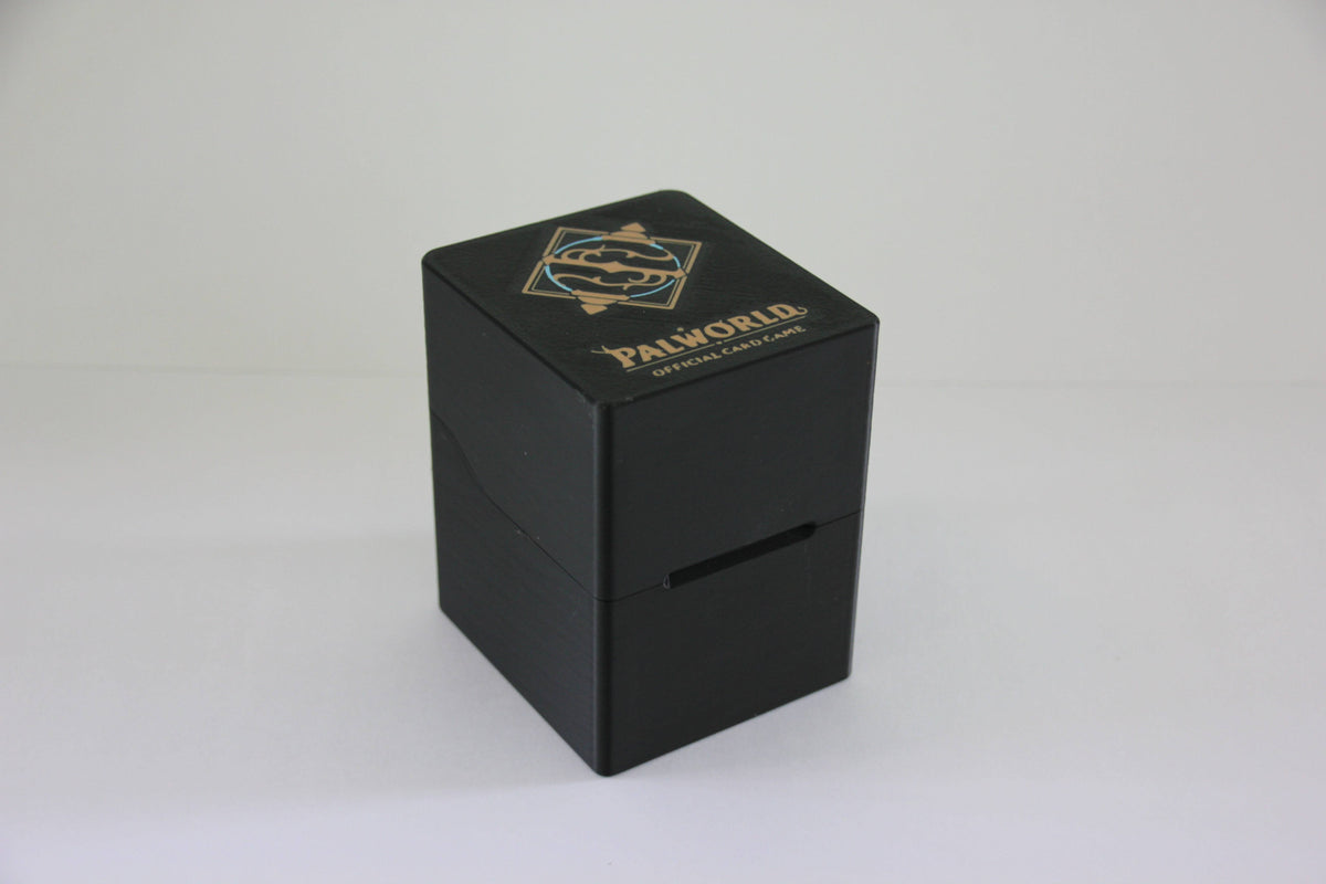 standard_palworld|Black 3D printed Palworld Official Card Game deck box closed, three-quarter view with the gold logo on the lid