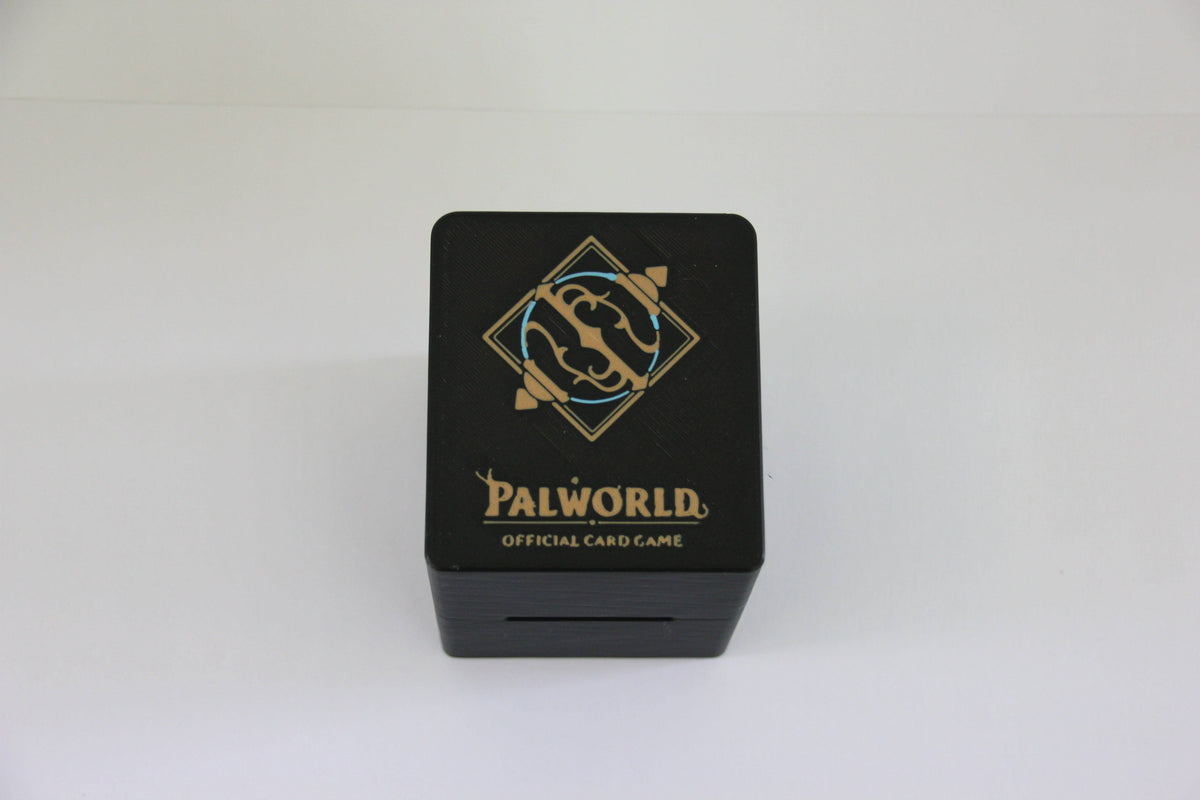 standard_palworld|Close-up of the gold and blue Palworld Official Card Game emblem on the deck box lid