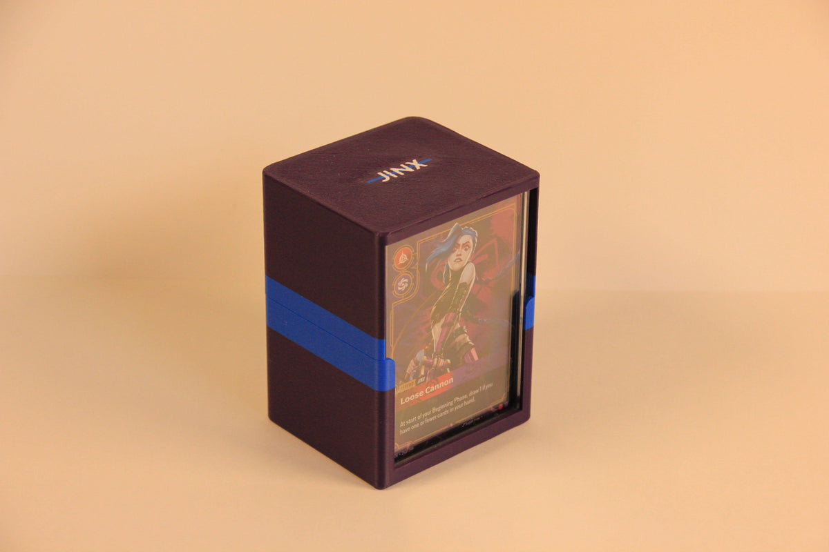 standard_riftbound|Purple and blue Riftbound Standard deck box closed, with a JINX nameplate lid, blue center stripe and a Loose Cannon card in the front display slot