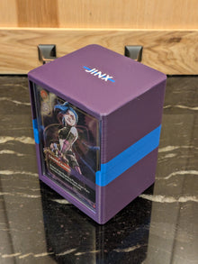 standard_riftbound|Riftbound Standard deck box closed, three-quarter view showing the JINX lid and the Jinx card in the side display window