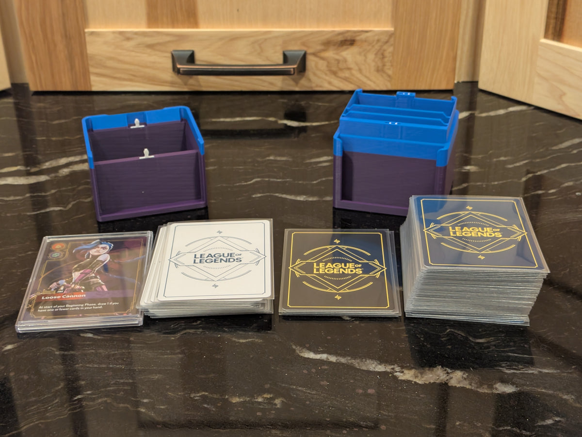 standard_riftbound|Both halves of the Riftbound Standard deck box empty, with battlefield, rune and unit card stacks laid out in front